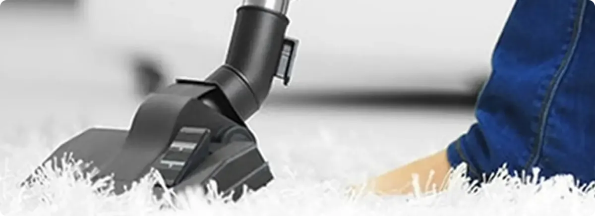 Close-up of a professional vacuuming a white carpet in Oracle.