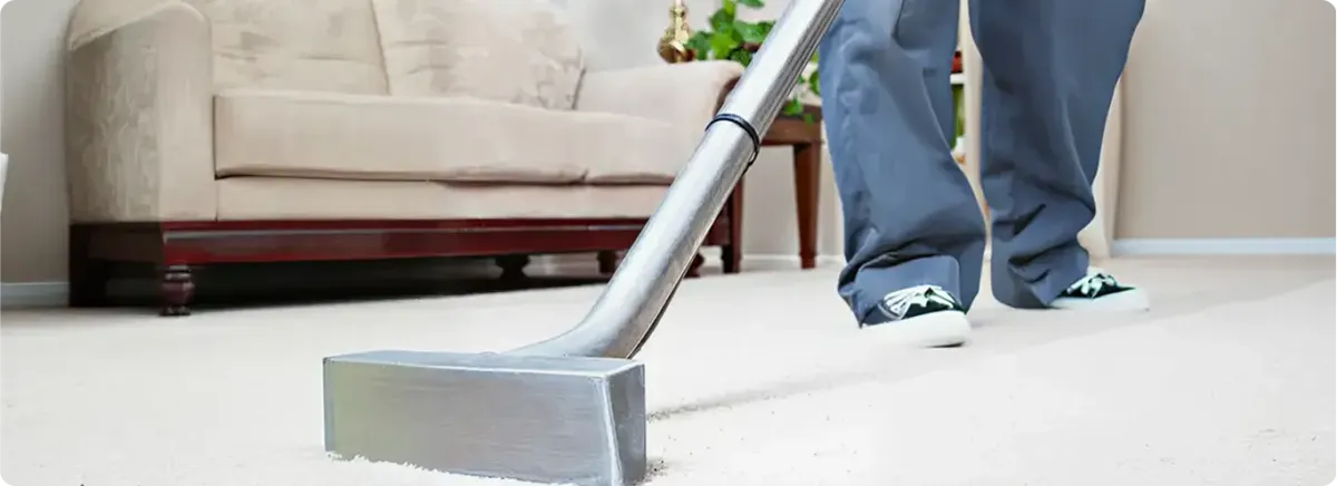 Carpet cleaning technician using a hot-water extraction wand on a light-colored carpet in a living room, Tucson, AZ.